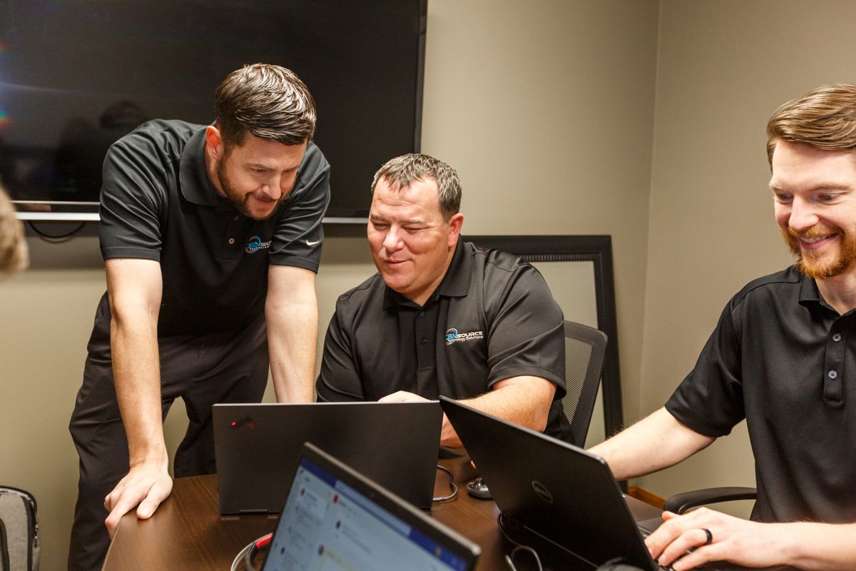 Two DEVsource employees smiling at a laptop screen